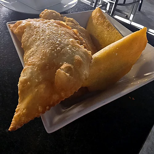 Golden fried cheese empanadas on a white square plate