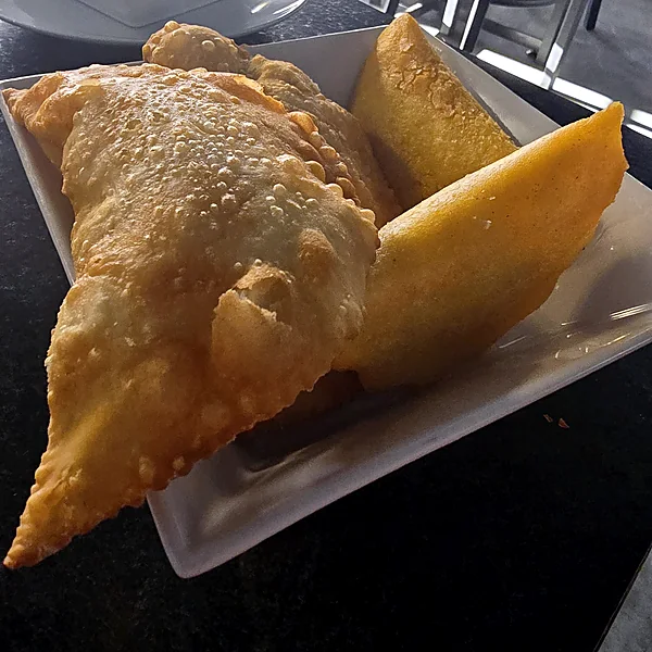 Golden fried cheese empanadas on a white square plate