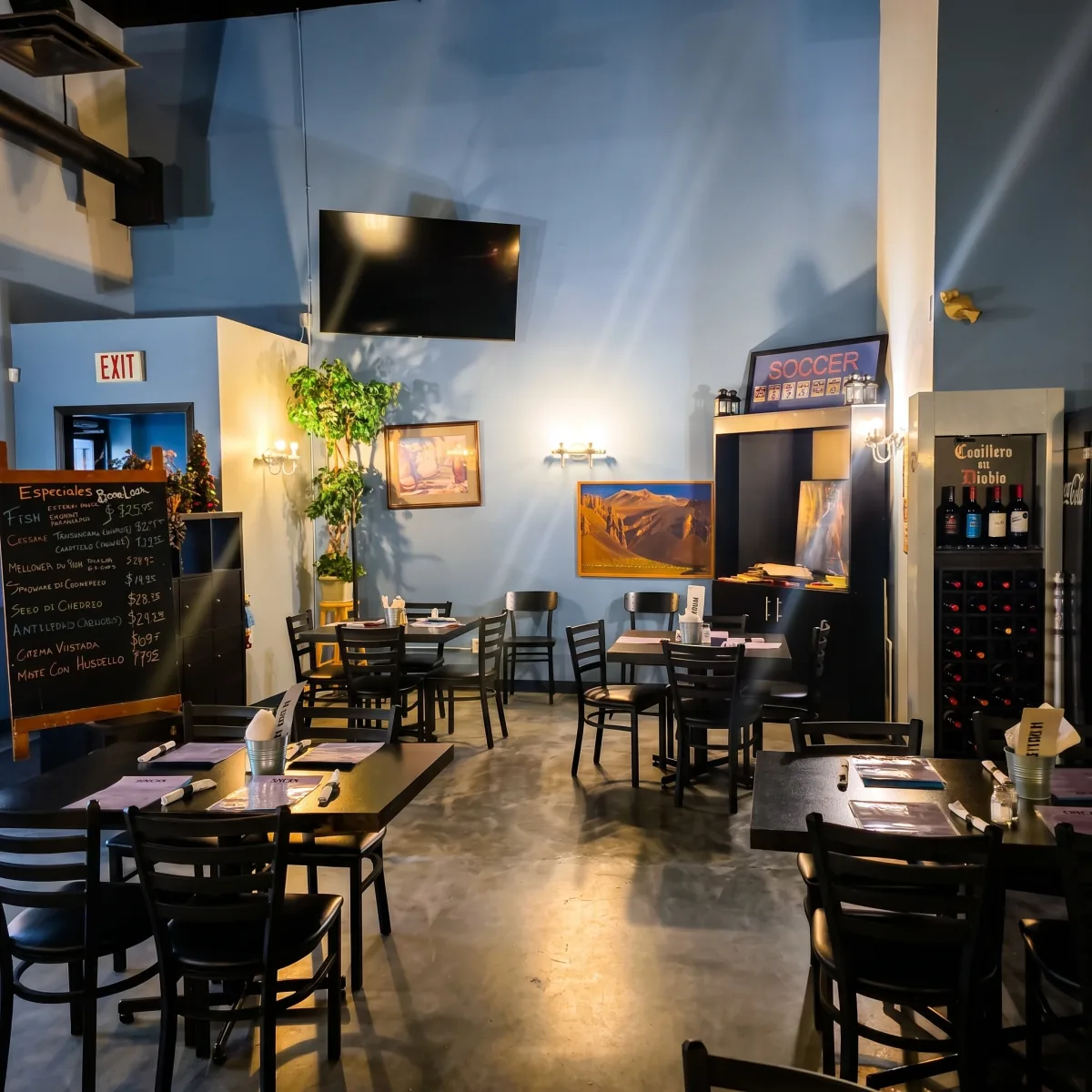 La Boca Loca dining room with blue walls, tables set for service and a chalkboard menu