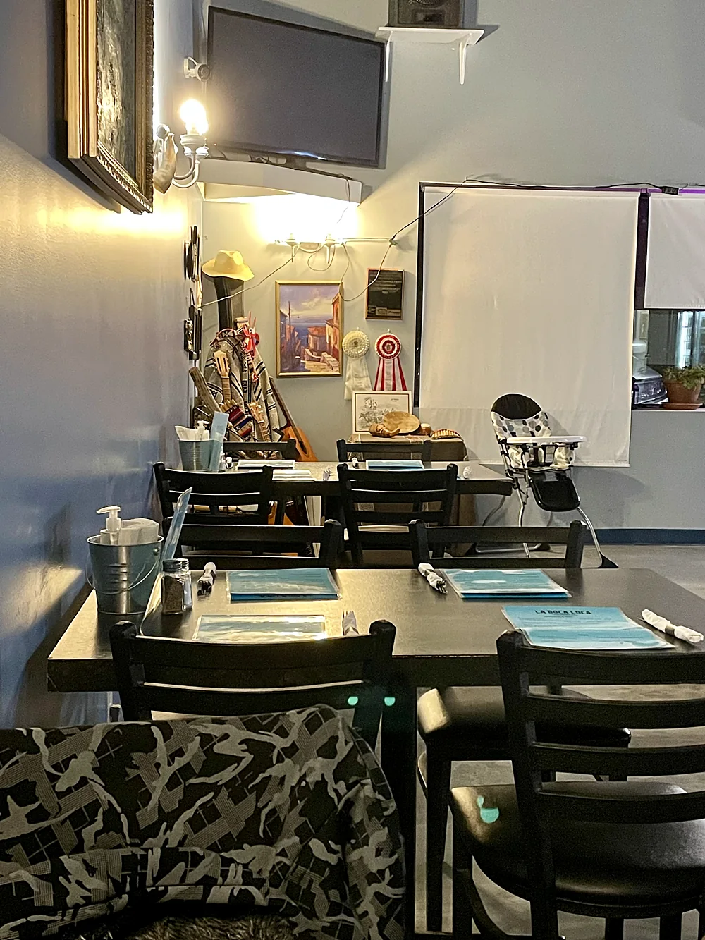 La Boca Loca dining room with dark tables, place settings and framed art